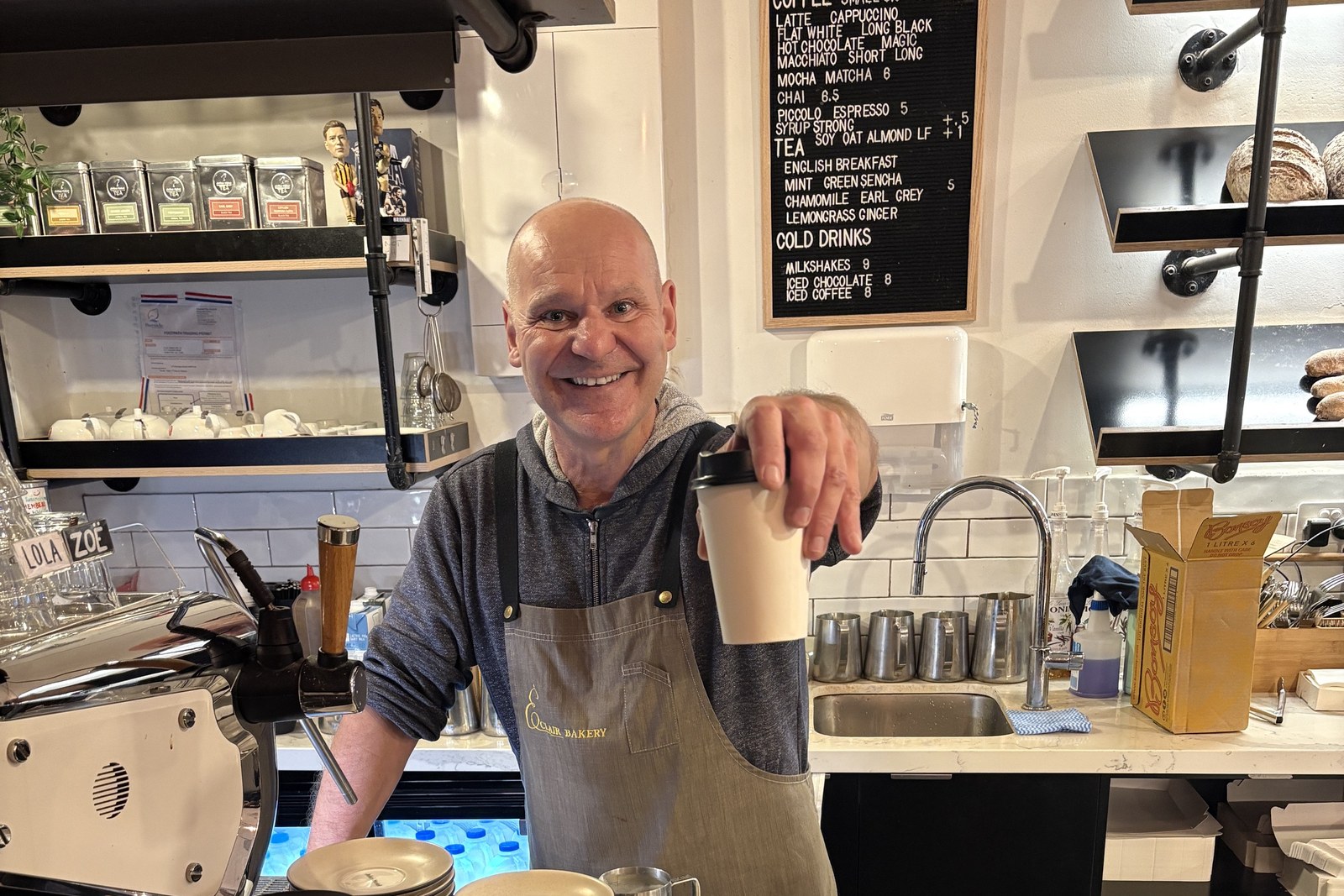 A barista at Éclair Boulangerie, Melbourne, handing over a takeaway coffee